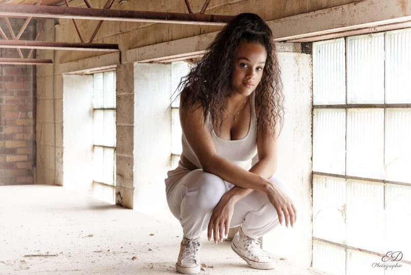 Jeune fille de couleur se tenant accroupie devant des fenêtres en blocs