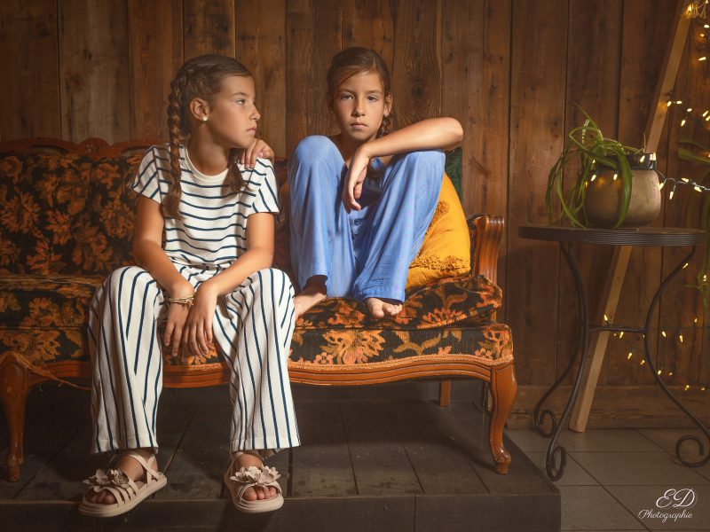 Jumelles assisses sur un sofa rétro