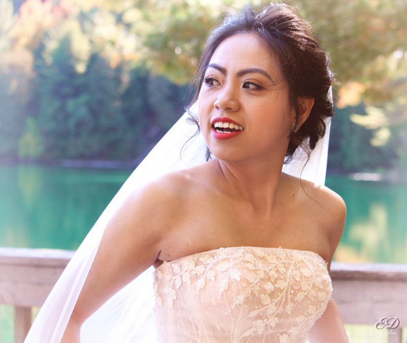 Mariée portant son voile et posant devant un lac