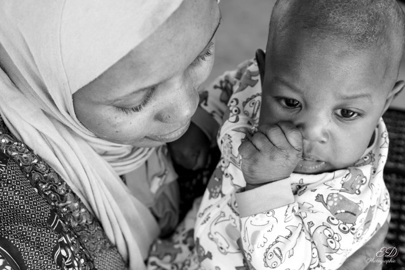 Femme portant un voile tient son enfant dans ses bras
