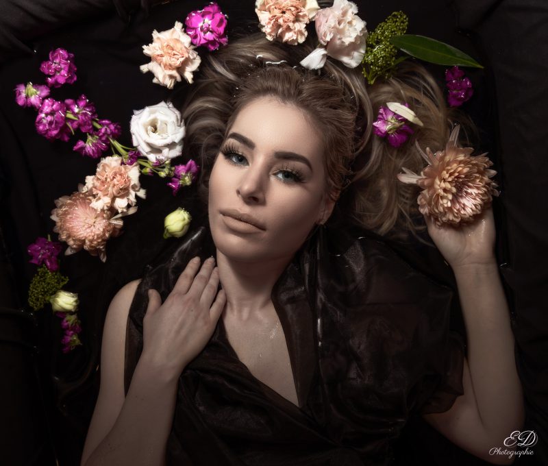 Jeune femme dans l'eau entourée de fleurs
